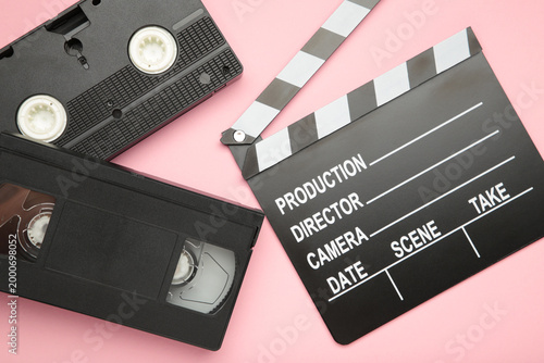 Retro Movie clapper board and video cassette on pink background. Filmmaking, Movie production. 80s.