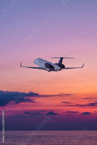 Executive aircraft take off over the ocean against the backdrop of scenic sunset sky