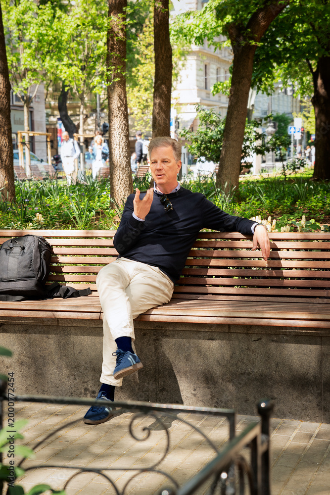 Fototapeta premium Confident man sitting in the city park and using his smartphone