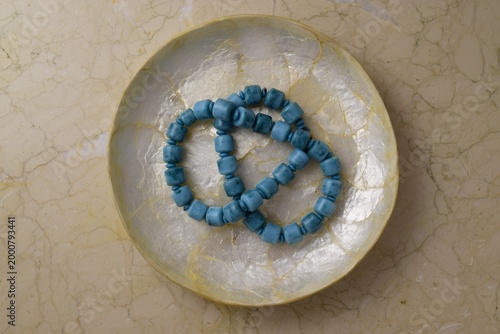 Decorative dish with turquoise necklace on marble background