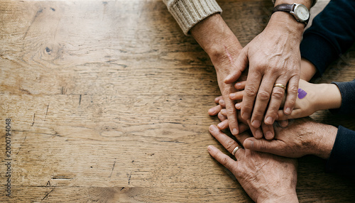 Foto An overhead view of multiple hands of different ages joined together on a wooden table, symbolizing family unity and connection across generations