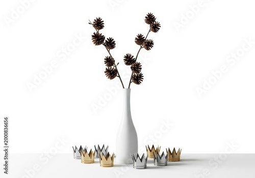 Tall white vase with black decorative pine cone branches and small paper crowns arranged on a flat surface area