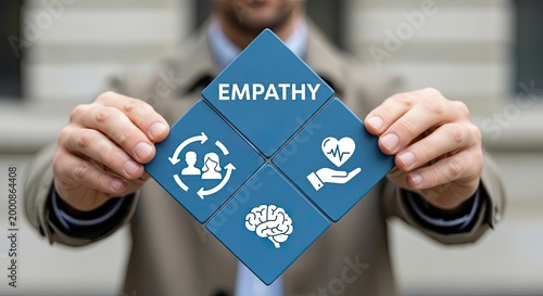 A person in a beige jacket holds a diamond-shaped configuration of four blue tiles labeled with the word empathy and human-centered icons on a neutral background.