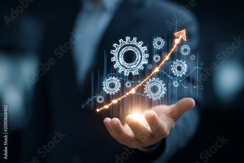 The business person's hands are displaying glowing gears and upward pointing arrows on a graph representing control, business process efficiency, and industry growth.