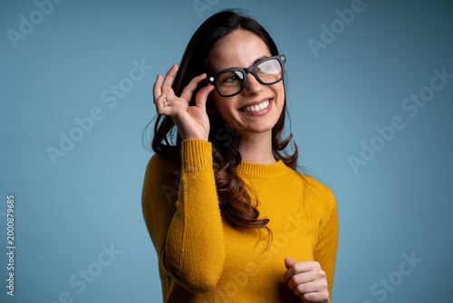 Cheerful woman using AR AI smart glasses highlighting innovative tech on blue