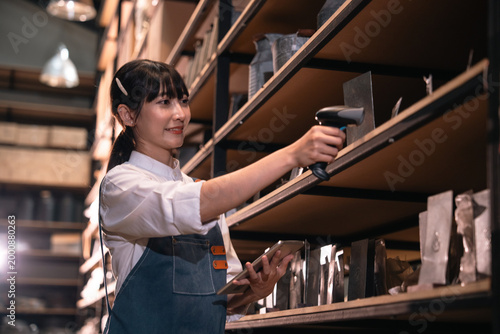 Foto Young woman scanning shelf in storage room with handheld scanner and clipboard,