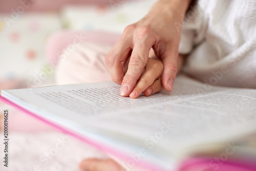 Mother and child hands touching open book page, sharing education, connection, and family learning moment