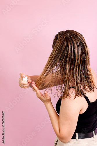 a woman applies styling product to wet hair