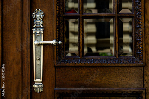 Slika na platnu Ornate silver handle on carved wooden doors with glass inserts