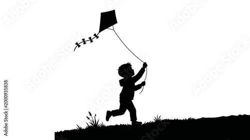 Silhouette of a happy young child playing with a kite.