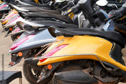 Row of parked scooters in bright colors available for rent in Goa, India, showcasing convenient tourist transport and urban mobility options.
