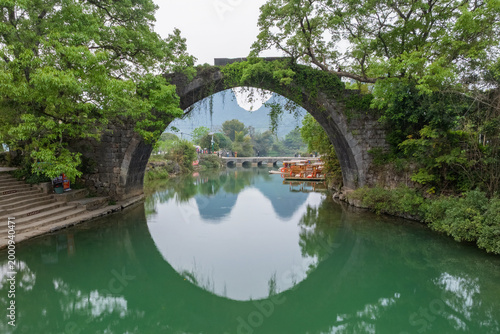 Close up amazing stone arch Fuli Bridge spans calm green river.