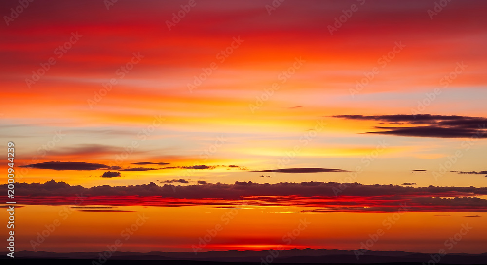 Fototapeta premium vibrant orange and red sunset with clouds