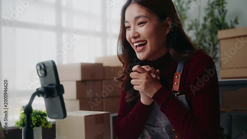 Young asian business owner live streaming on a smartphone for her online business from a home office