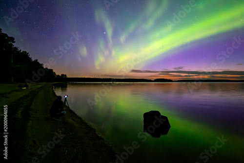 Anazing aurora borealis in the starry sky dancing over calm lake