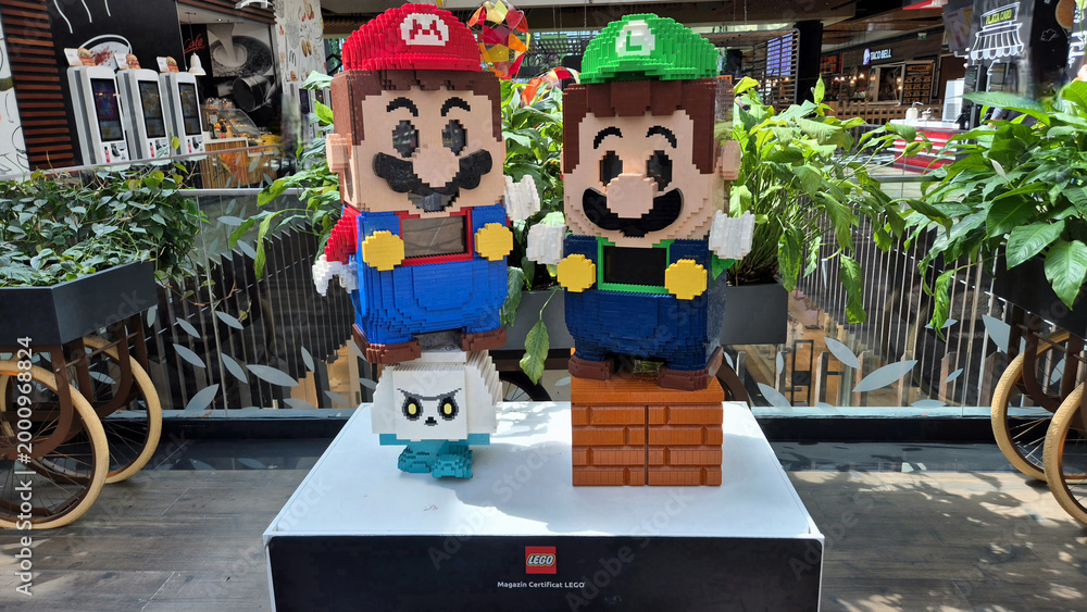 Obraz premium Lego statues of Mario and Luigi standing on a Goomba and a brick block inside a brightly lit shopping mall display. Picture taken on April 27, 2026 in Bucharest, Romania.