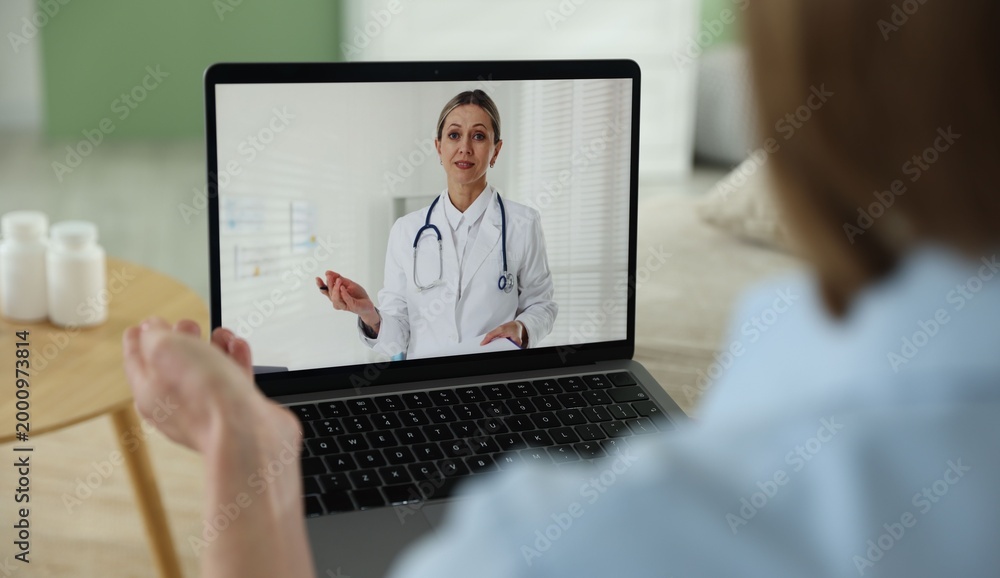 Fototapeta premium Telemedicine. Woman having online consultation with doctor via laptop at home, closeup