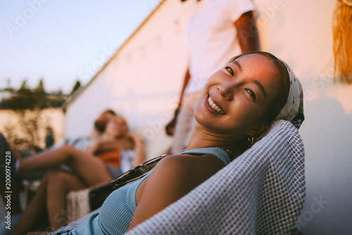 Foto Young asian woman smiling relaxing with friends at sunset party