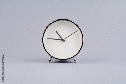 A clock standing still against a gray background, a studio photograph. Concept of time and daily life.