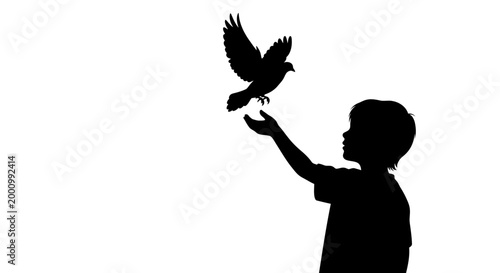 Silhouette of a young boy releasing a dove representing peace and freedom.