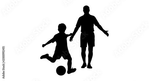 Silhouette of a father coaching his young son playing soccer.