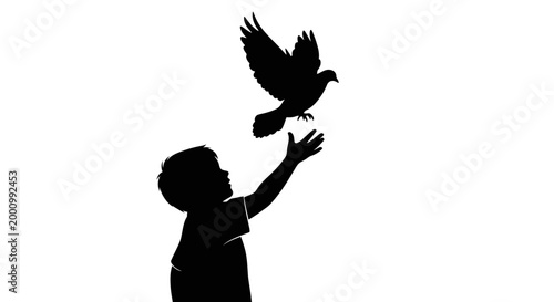 Silhouette of a young child releasing a bird into the air.