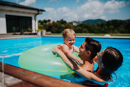 Photos Parents and child having fun with floatie in garden swimming pool