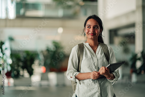 Photography Young indian student smiling and carrying backpack and digital tablet in a moder