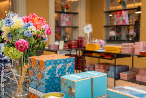 фотографія Warm boutique in Grasse, France presents pastel gift boxes, floral displays, reed diffusers, and perfume items on black tables and shelves with turquoise gold accents