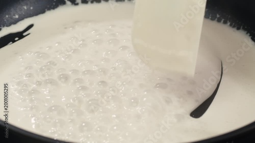 Boiling cream, boil yogurt swirl milk white lotion splash on pan. Cooking white sauce.