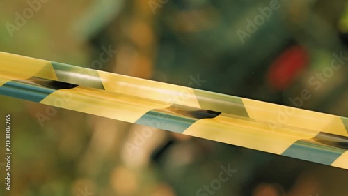 Close up shot of yellow black striped caution tape. Diagonal composition creates visual tension. Soft light highlights plastic texture. Blurred background suggests outdoor setting restricted area