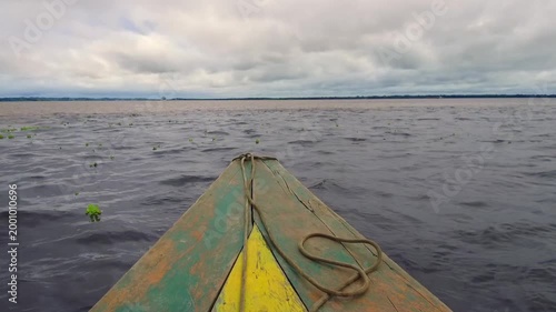 POV boat ride on Amazon River with wooden canoe and water surface under cloudy sky