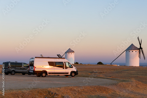 Camper vans parked near historical windmills at sunset in Campo de Criptana