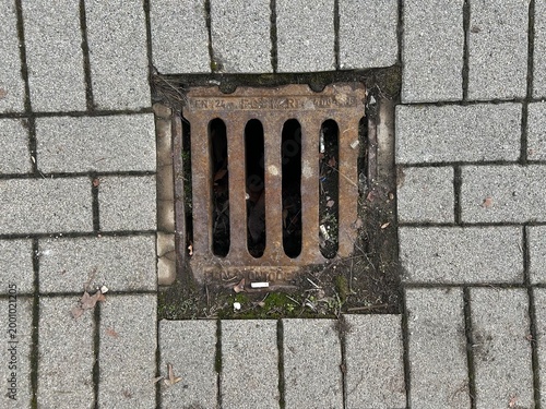 Urban surface and infrastructure texture. Rusty rain water drainage at city road.