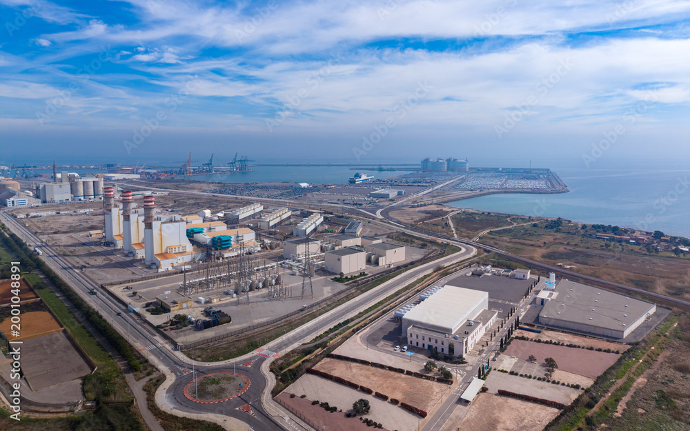 Fototapeta premium Aerial view of large coastal industrial complex featuring a combined cycle gas power plant, water distillation station, electrical substation, and commercial seaport with cranes along the Mediterranea