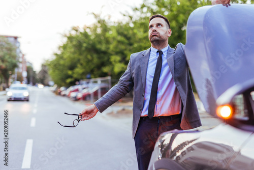 Billede på lærred Businessman With Broken Car Stands Frustrated On Roadside Holding Glasses While