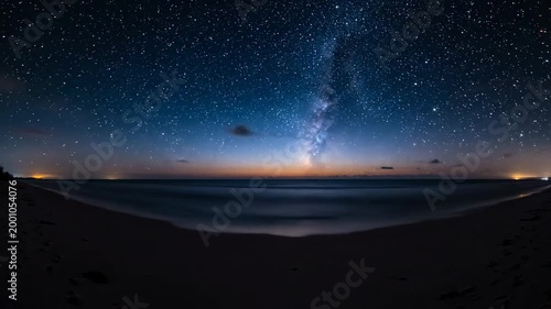 This captures a breathtaking beach scene at sunset, with a starry night sky and vibrant colors in the clouds. The serene atmosphere and peaceful waves create a sense of tranquility and relaxation.