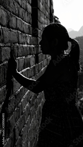 Silhouette of a person touching a brick wall with mountains in the background scenery