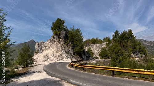Mountain road near Skadar Lake curves around rocky ridge with pine trees
