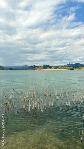 Fort Lesendro ruins on Shkodra Lake shoreline with spring reeds and distant hills