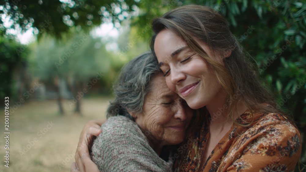 Fototapeta premium Young Woman Hugging Elderly Mother in Garden