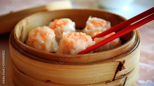 Steamed dumplings in bamboo steamer with red chopsticks close up