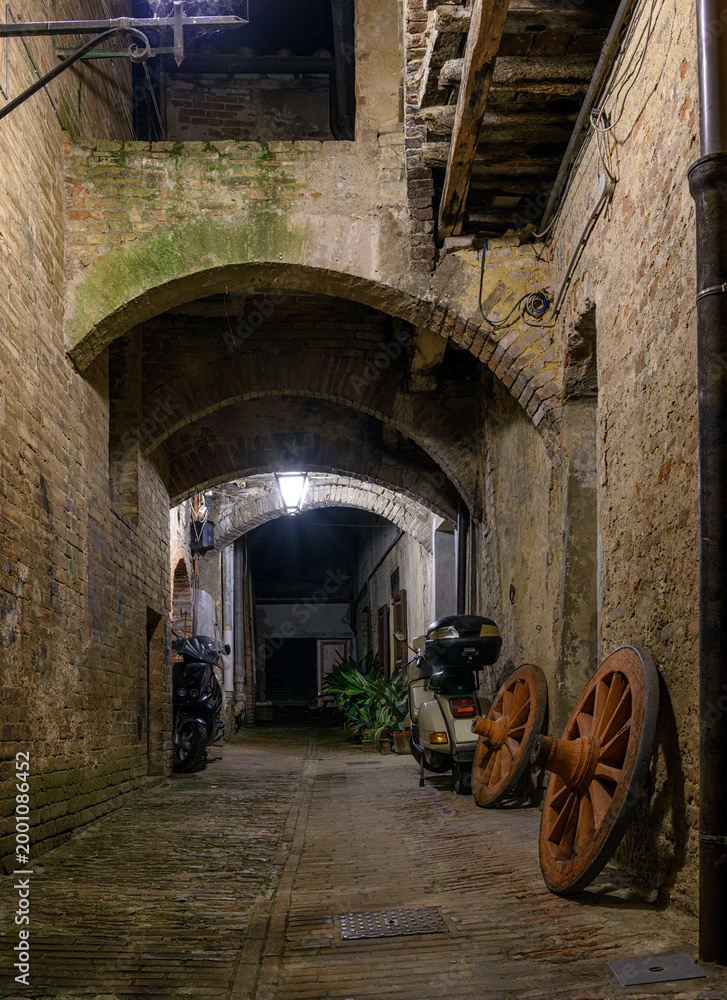 Fototapeta premium Medieval narrow street in Siena at night, Tuscany, Italy. Architecture and landmark of Siena. Cozy cityscape of Siena