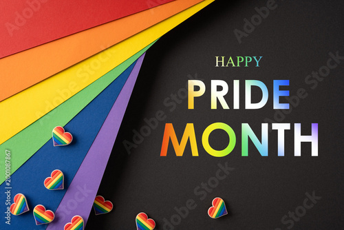 Pride month concept with rainbow paper layers and heart pins on a black background