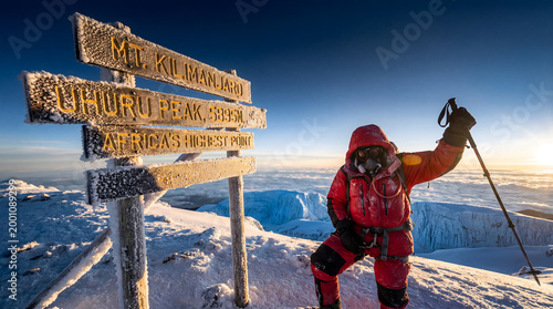 Climber reaching uhuru peak summit on mount kilimanjaro
