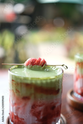 Strawberry matcha dessert in glass with raspberries on top, outdoor setting