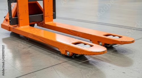 Warehouse logistics equipment featuring the sturdy orange forks of a manual pallet jack.