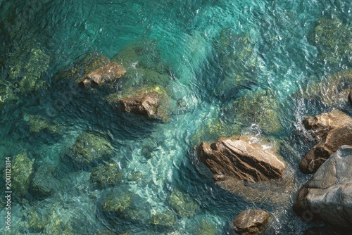 Clear turquoise water flows over smooth, rounded rocks in a natural setting
