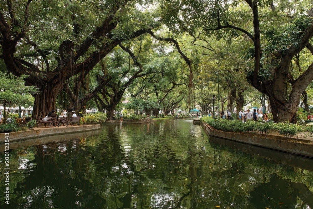 Fototapeta premium Lush green park with calm water canal and ancient trees