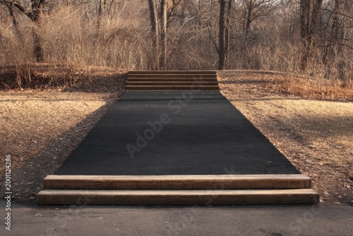 A long, dark path leads up wooden steps and into a bare, treed landscape